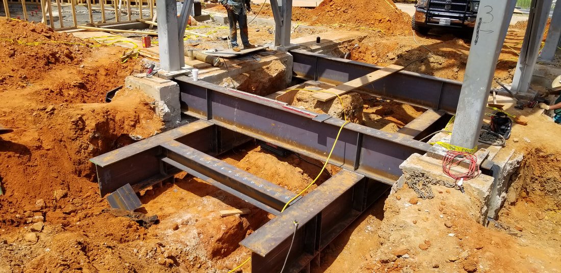 Structural steel foundation framing set in an excavation beside steel columns