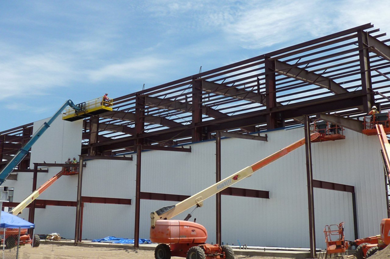 Structural steel manufacturing facility with lifts and wall panels being installed